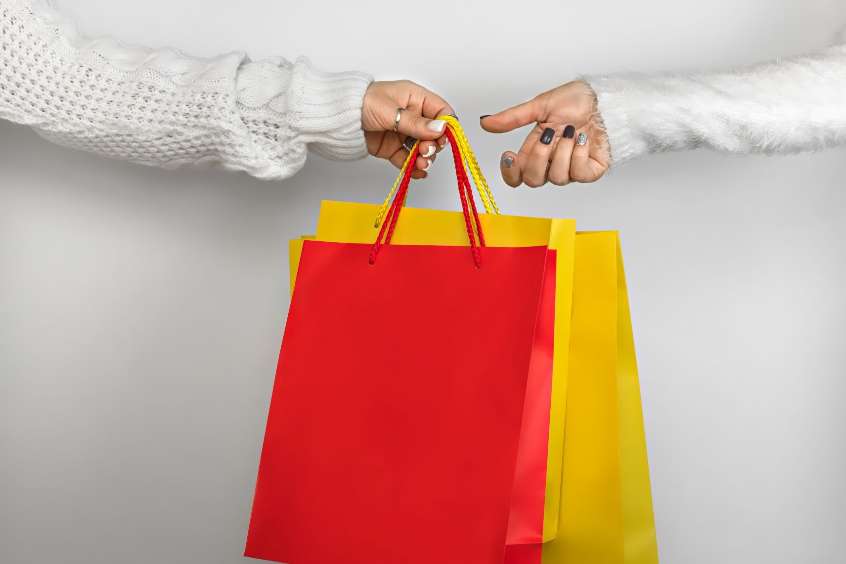 Dois braços trocando sacolas de compras em cores diferentes